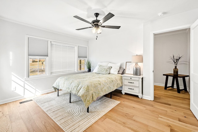 bedroom with light wood-style floors, visible vents, baseboards, and a ceiling fan