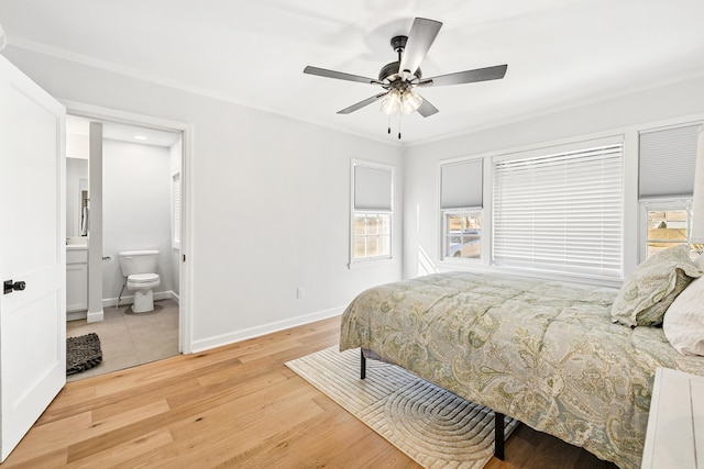 bedroom featuring a ceiling fan, ornamental molding, ensuite bath, wood finished floors, and baseboards