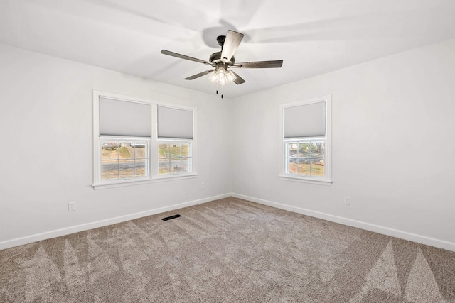 empty room with baseboards, carpet flooring, visible vents, and a healthy amount of sunlight