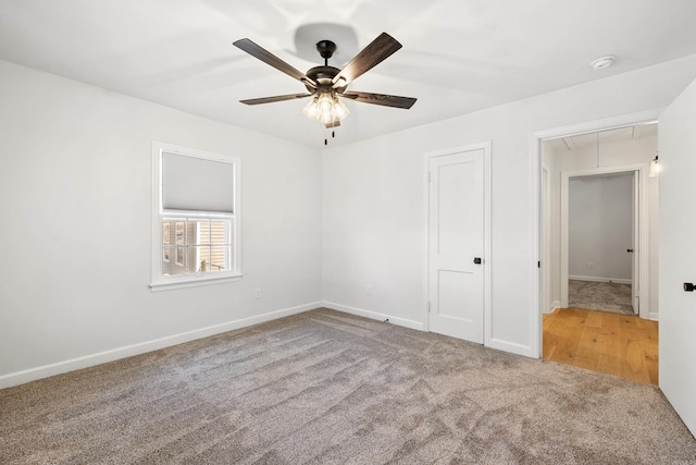 unfurnished bedroom with carpet, attic access, baseboards, and a ceiling fan