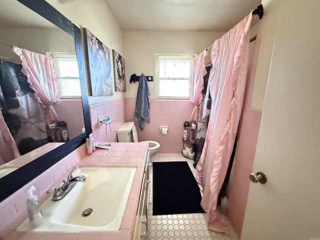 full bathroom featuring toilet, a wainscoted wall, a wealth of natural light, and tile walls