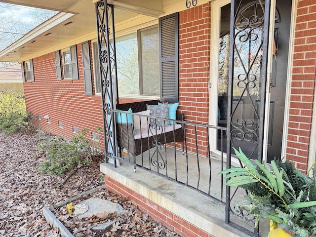 doorway to property with crawl space, brick siding, and covered porch