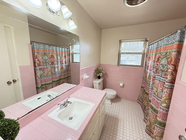 bathroom with wainscoting, tile walls, and toilet