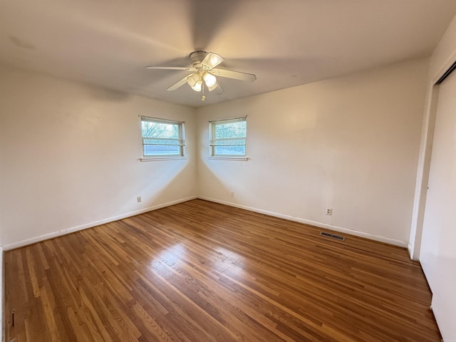 spare room with baseboards, visible vents, ceiling fan, and wood finished floors