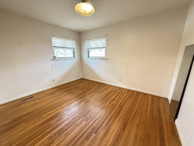 empty room featuring baseboards, visible vents, and light wood-style floors