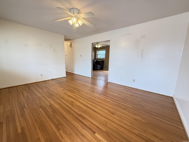 spare room featuring ceiling fan, light wood-type flooring, and baseboards