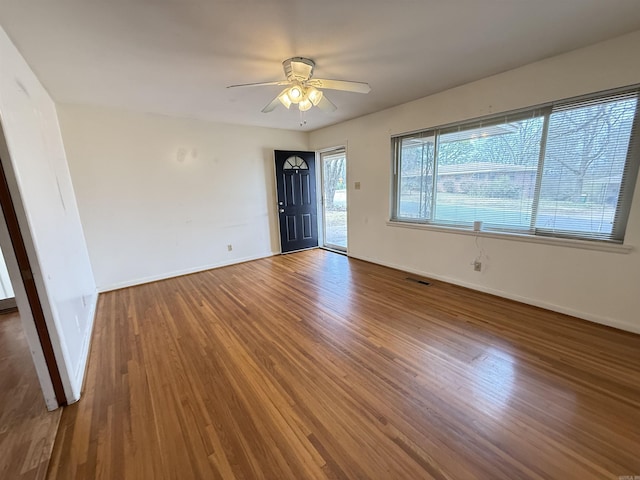 empty room featuring ceiling fan, baseboards, and wood finished floors