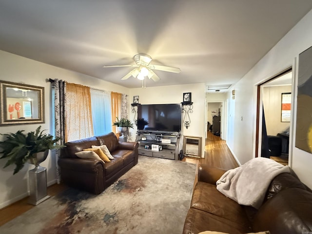 living area featuring ceiling fan, baseboards, and wood finished floors