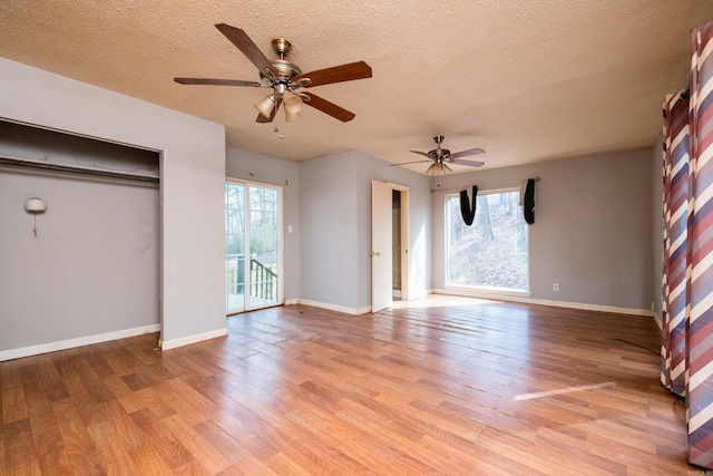 unfurnished bedroom featuring light wood-style floors, access to outside, a textured ceiling, and baseboards