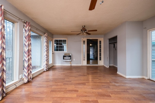 interior space featuring heating unit, light wood finished floors, a healthy amount of sunlight, and a ceiling fan