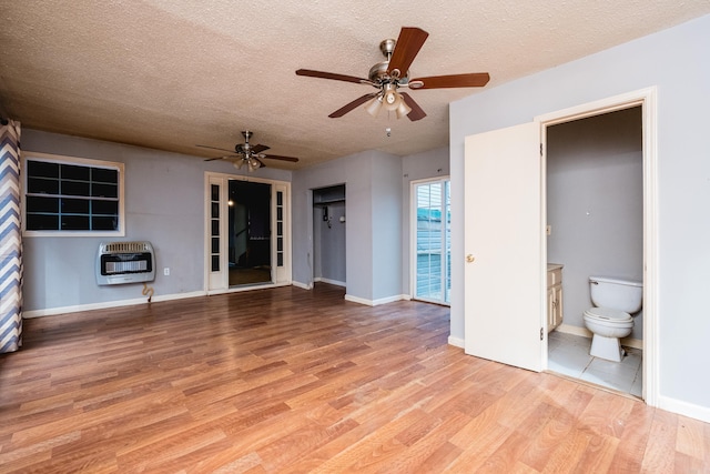 interior space with a textured ceiling, baseboards, light wood-style flooring, and heating unit