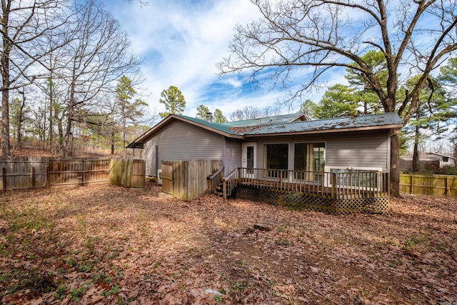 back of property featuring a fenced backyard, metal roof, and a wooden deck