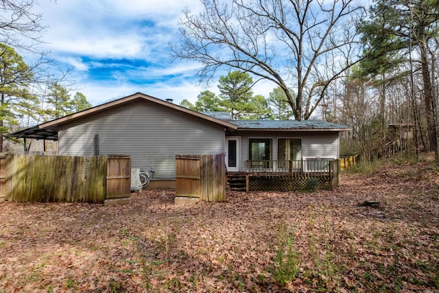 rear view of house with a deck, metal roof, and fence