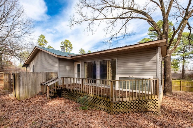 back of property with a deck, metal roof, and fence