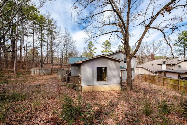 back of property featuring fence and metal roof