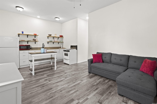 living room featuring baseboards, recessed lighting, and light wood-style floors