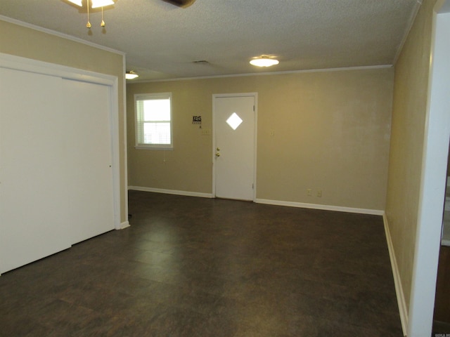 foyer with a textured ceiling, dark floors, ornamental molding, and baseboards