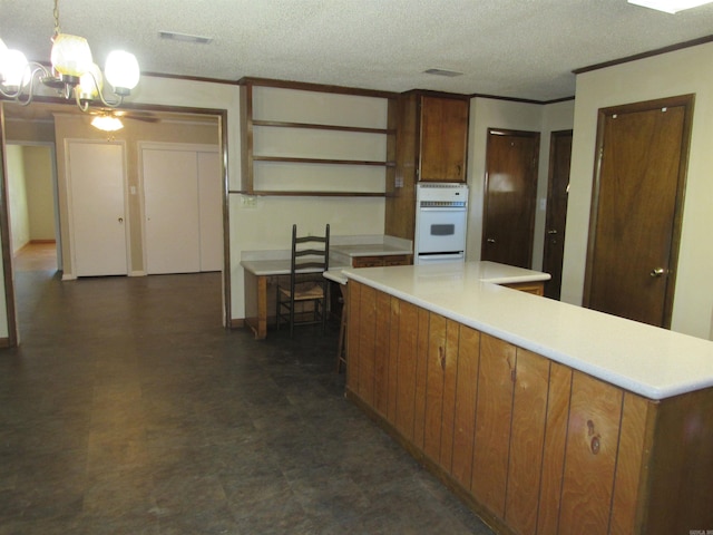 kitchen with light countertops, brown cabinetry, crown molding, and oven