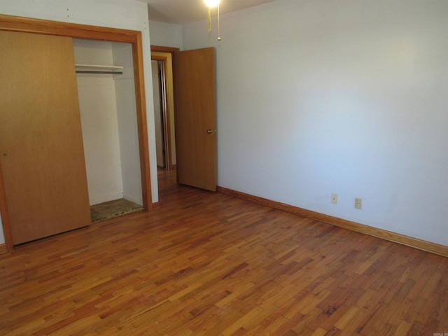 unfurnished bedroom featuring a closet, light wood-style flooring, and baseboards