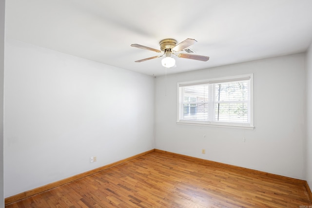 spare room featuring ceiling fan, light wood-type flooring, and baseboards