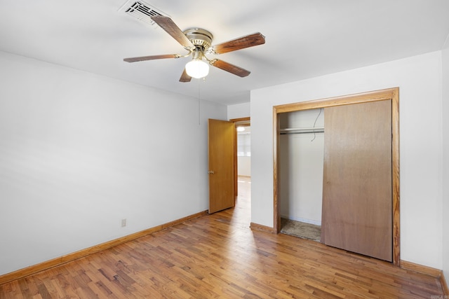 unfurnished bedroom featuring a closet, visible vents, ceiling fan, wood finished floors, and baseboards