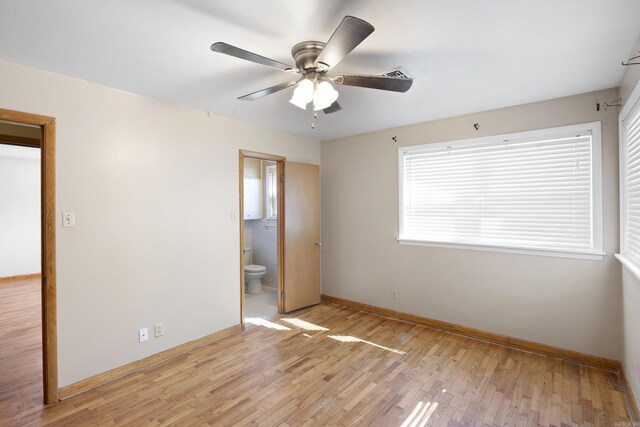 unfurnished bedroom featuring connected bathroom, wood finished floors, a ceiling fan, visible vents, and baseboards