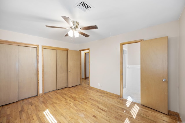 unfurnished bedroom featuring light wood-style floors, a ceiling fan, visible vents, and two closets