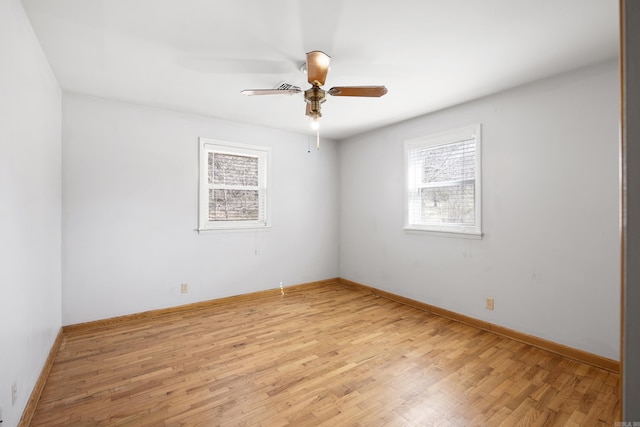 empty room with ceiling fan, light wood finished floors, and baseboards