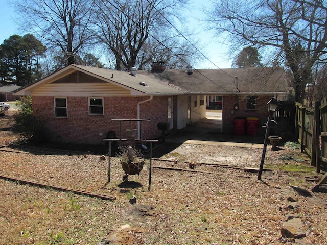 rear view of property with a chimney and brick siding