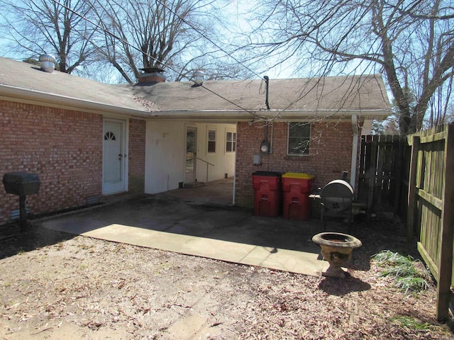 back of house featuring a patio area, a chimney, fence, and brick siding