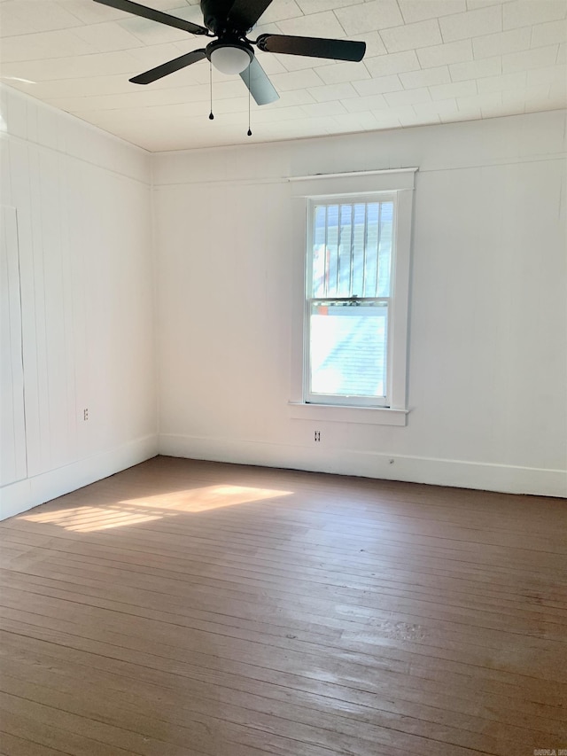 empty room featuring wood finished floors, a ceiling fan, and baseboards