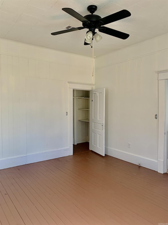 empty room featuring ceiling fan, baseboards, and wood finished floors