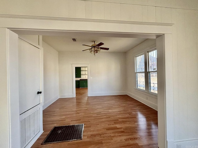 empty room featuring visible vents, ceiling fan, and wood finished floors