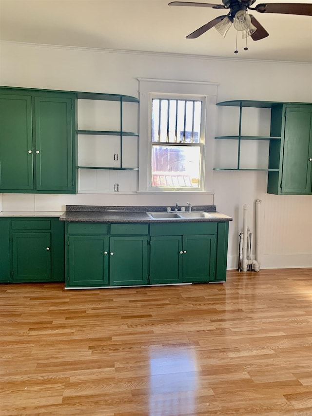 kitchen with open shelves, a sink, light wood-style flooring, and green cabinetry