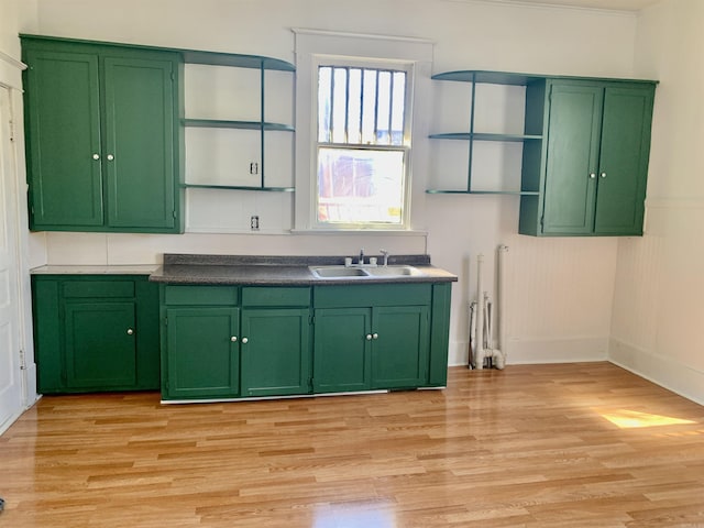 kitchen featuring light wood-style floors, green cabinetry, a sink, and open shelves