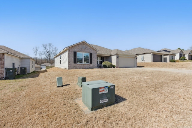 ranch-style house featuring a garage, central air condition unit, a front yard, and brick siding