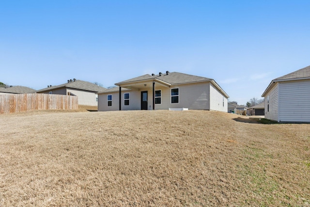 back of property featuring fence and a yard