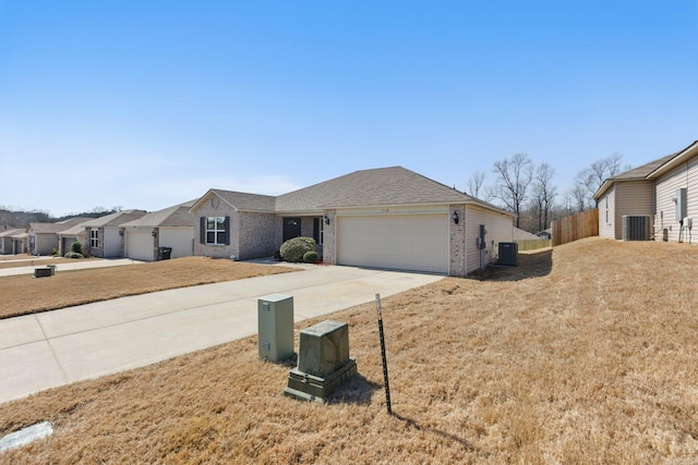 ranch-style home featuring driveway, an attached garage, cooling unit, and brick siding