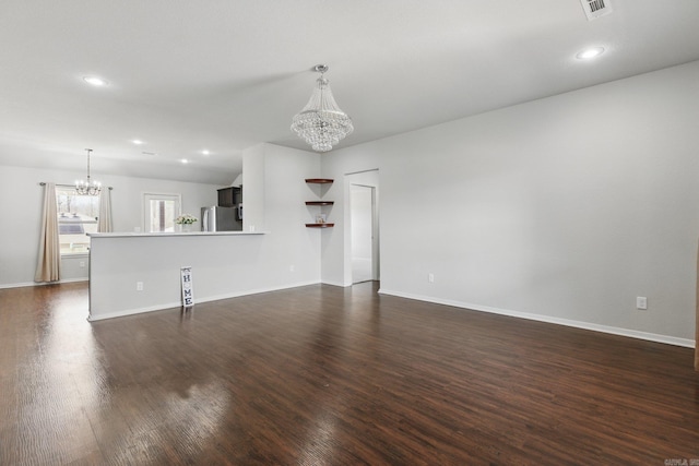 unfurnished living room with baseboards, dark wood-style flooring, a notable chandelier, and recessed lighting