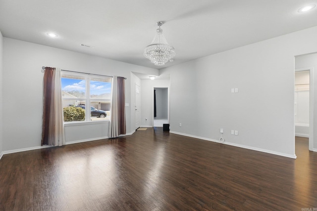 unfurnished room with an inviting chandelier, baseboards, and wood finished floors