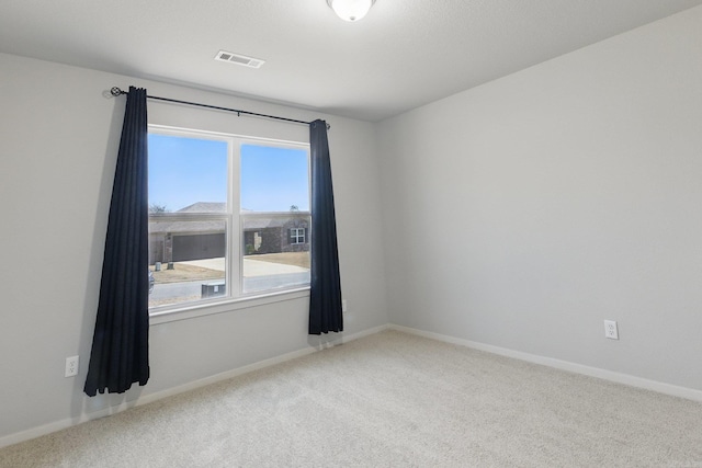 empty room featuring baseboards, visible vents, and carpet flooring