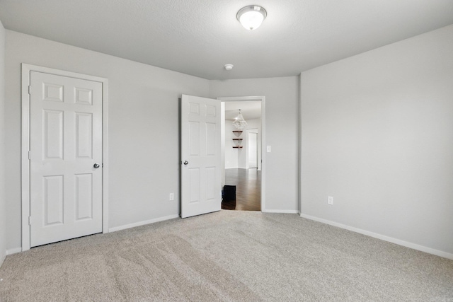 unfurnished bedroom with carpet, a textured ceiling, and baseboards