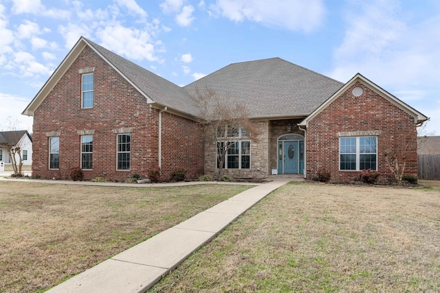 traditional-style house with roof with shingles, brick siding, and a front lawn