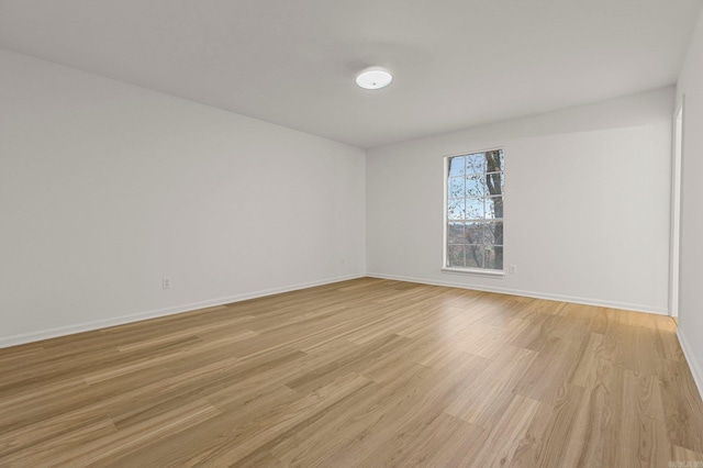 unfurnished room with light wood-type flooring and baseboards