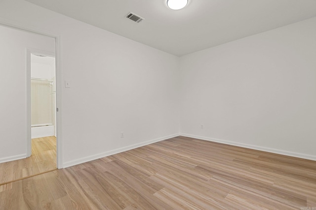 empty room featuring light wood finished floors, baseboards, and visible vents