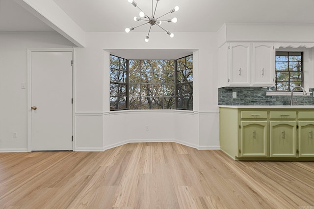 kitchen with a chandelier, a sink, light wood-style floors, green cabinets, and light countertops