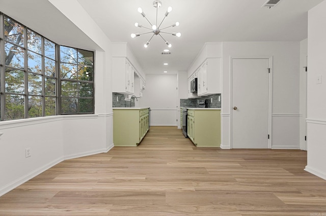 kitchen with green cabinetry, appliances with stainless steel finishes, backsplash, a notable chandelier, and a sink