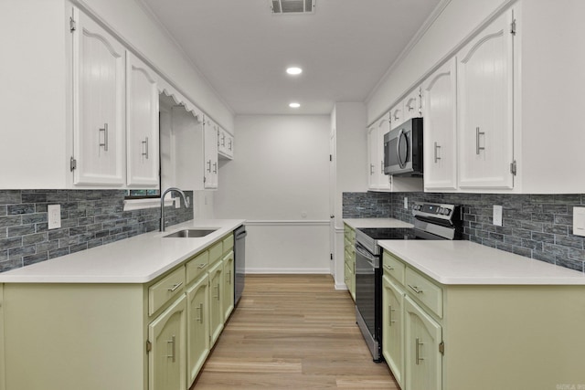 kitchen featuring green cabinets, stainless steel appliances, light wood-type flooring, and a sink