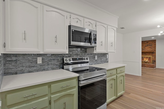 kitchen with decorative backsplash, light wood-style flooring, appliances with stainless steel finishes, light countertops, and green cabinetry