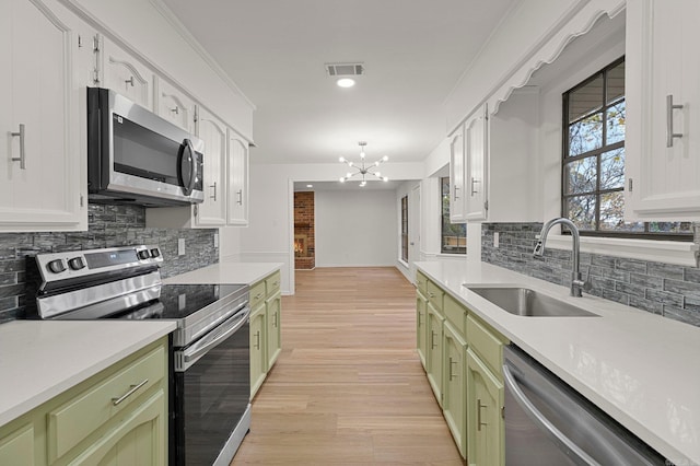 kitchen featuring a sink, visible vents, stainless steel appliances, and green cabinetry